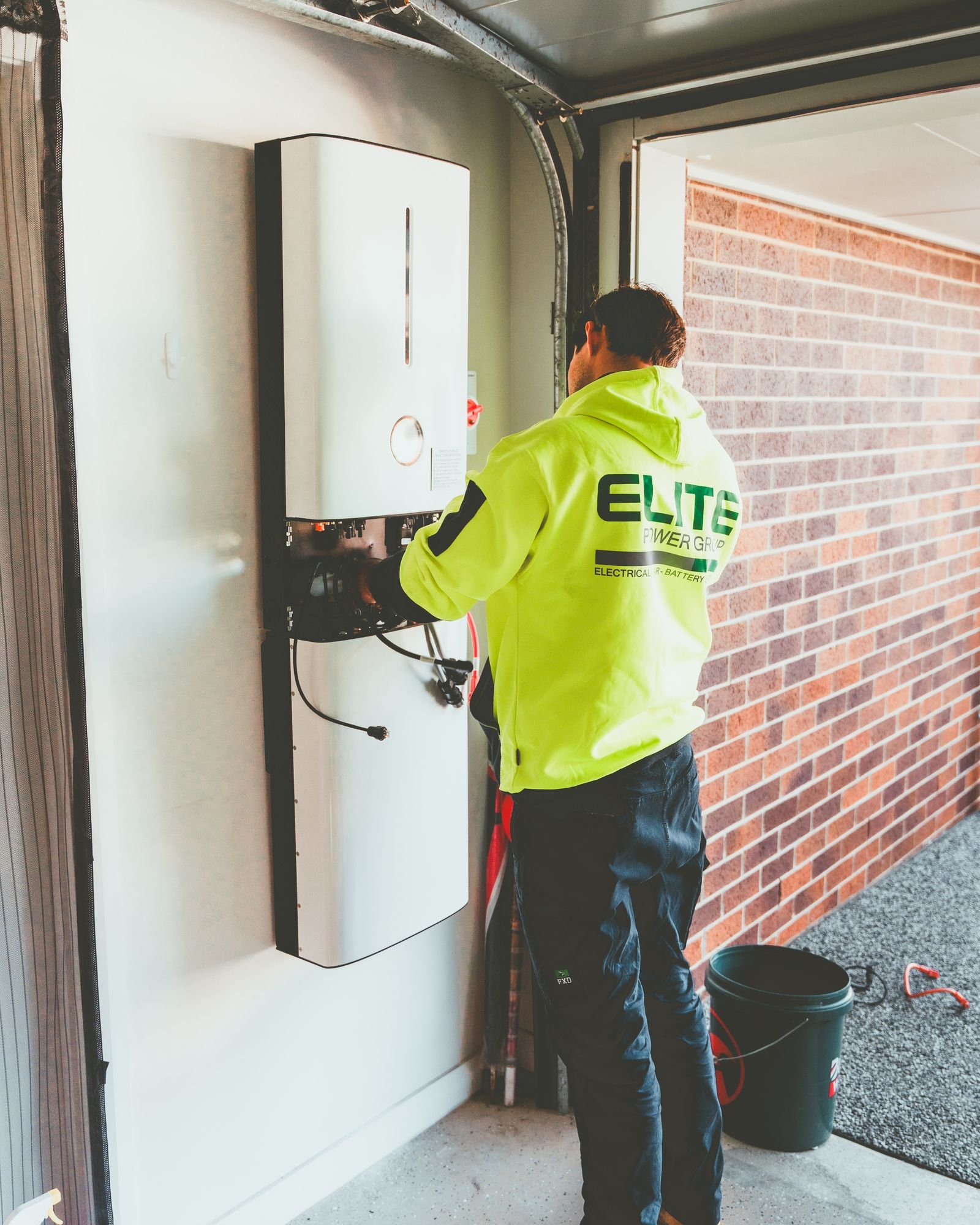 Two home batteries installed side by side on a garage wall
