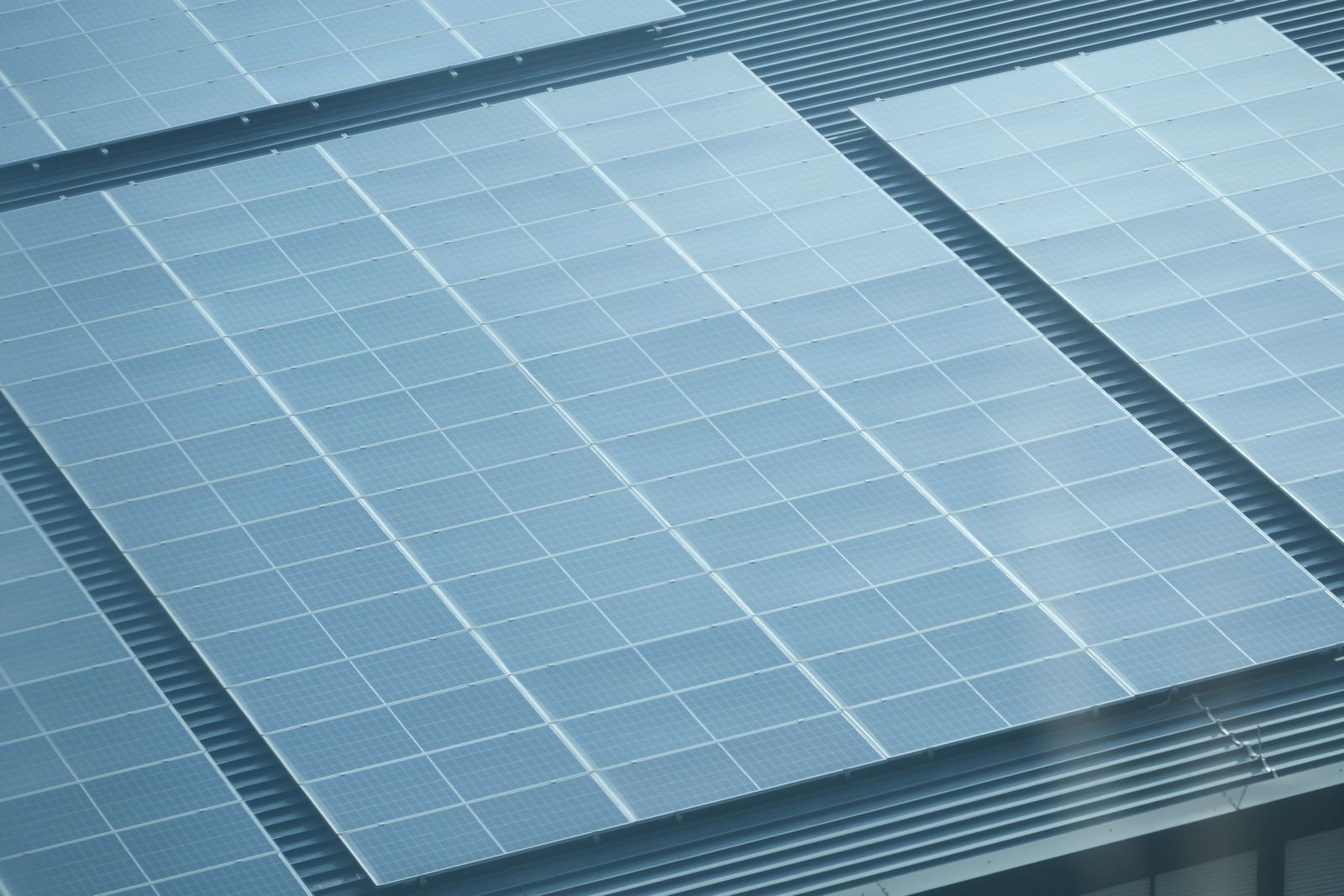 A microinverter mounted under a solar panel on a roof