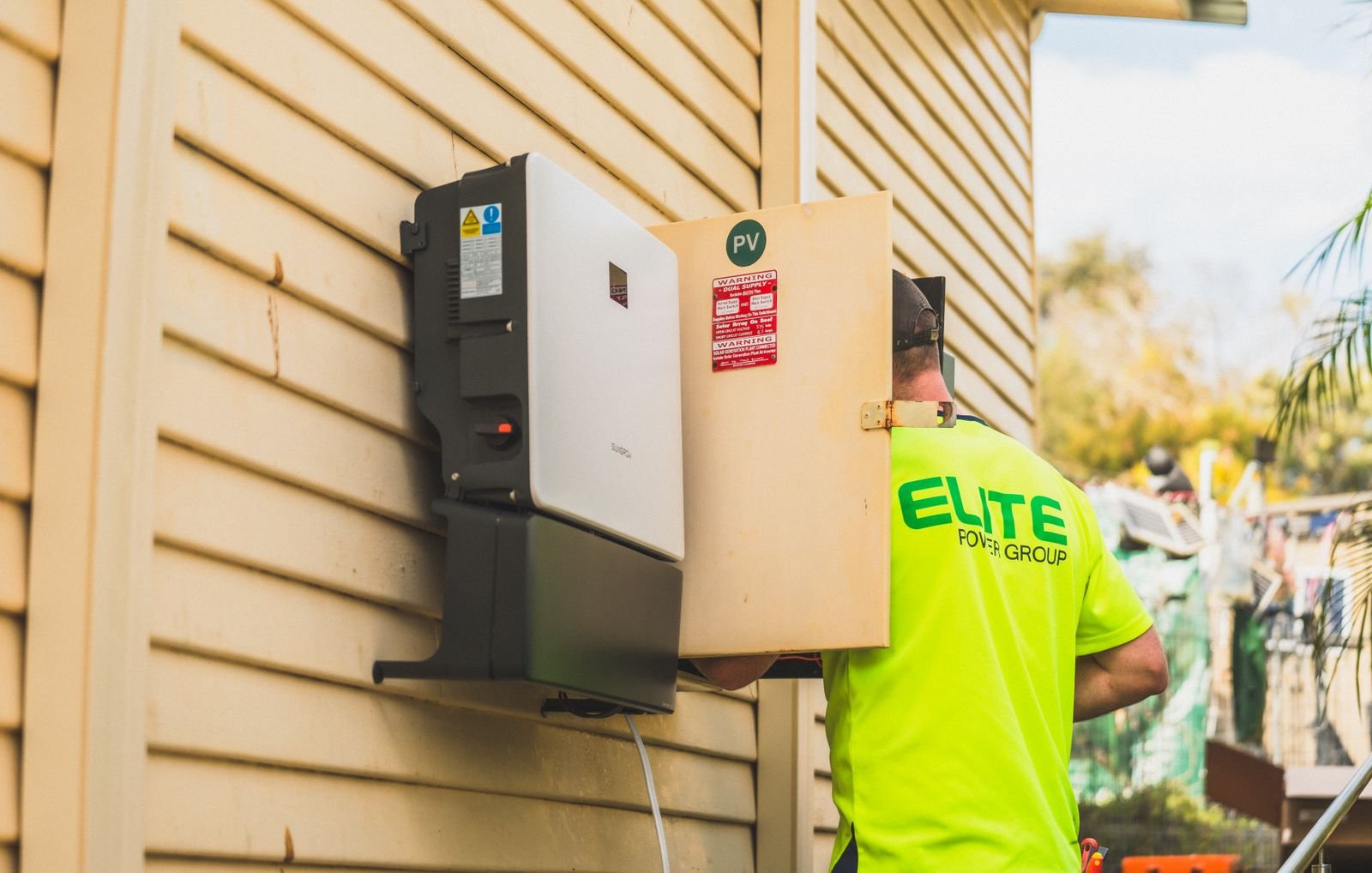 A wall-mounted string inverter beside a home's electrical panel