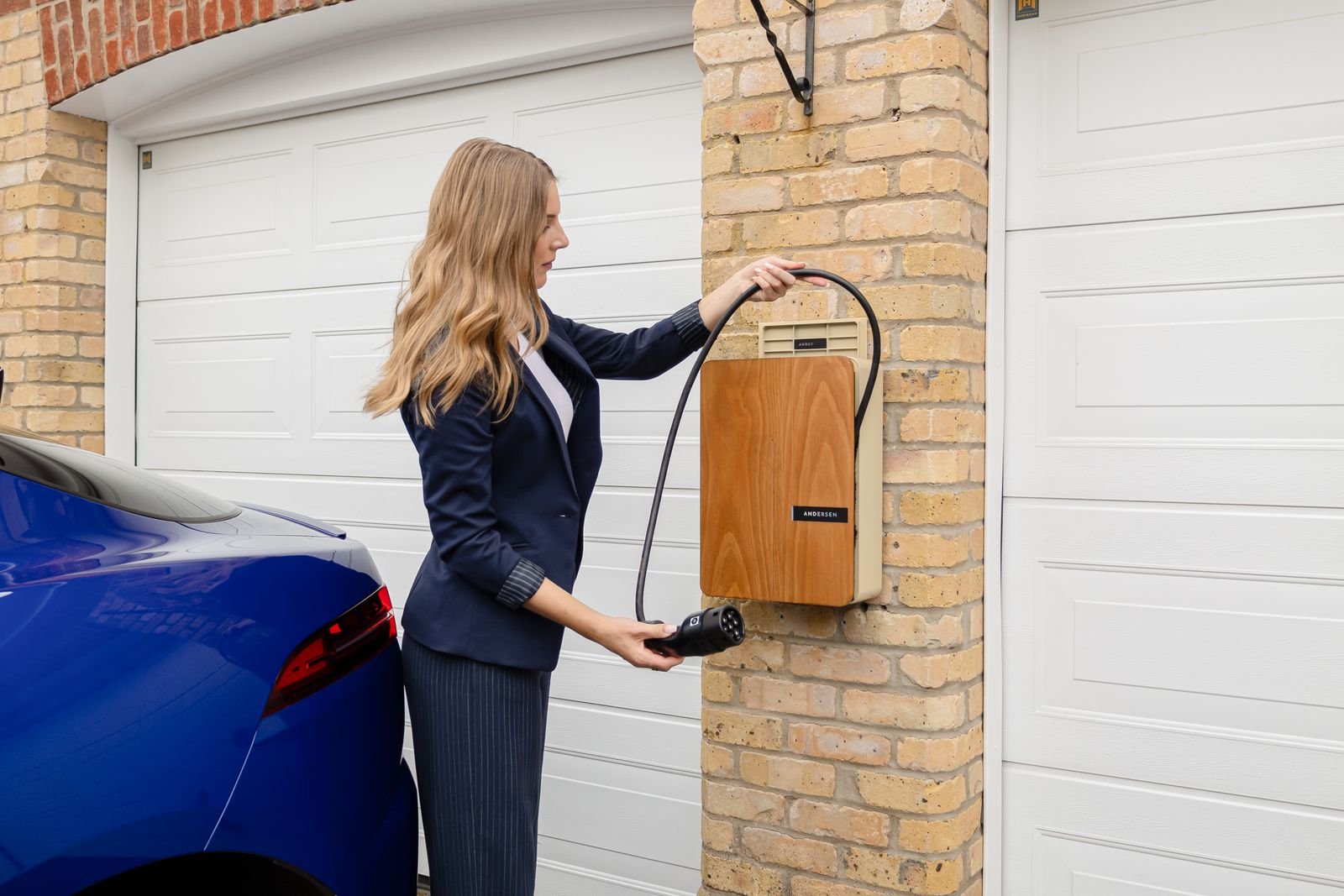 Electrician mounting a Level 2 EV wall charger in a home garage