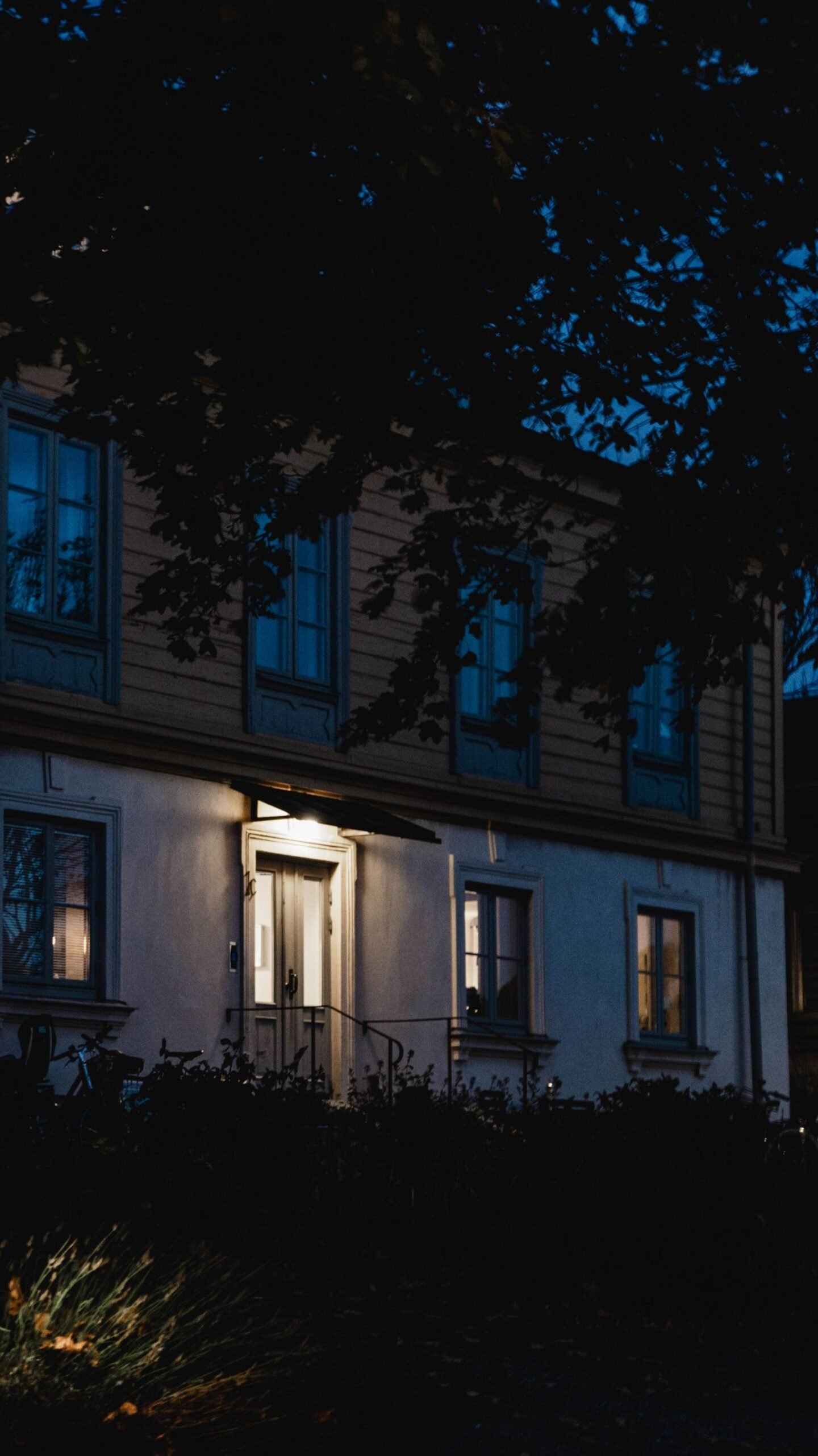 A single lit house at night on an otherwise dark street during a neighborhood power outage