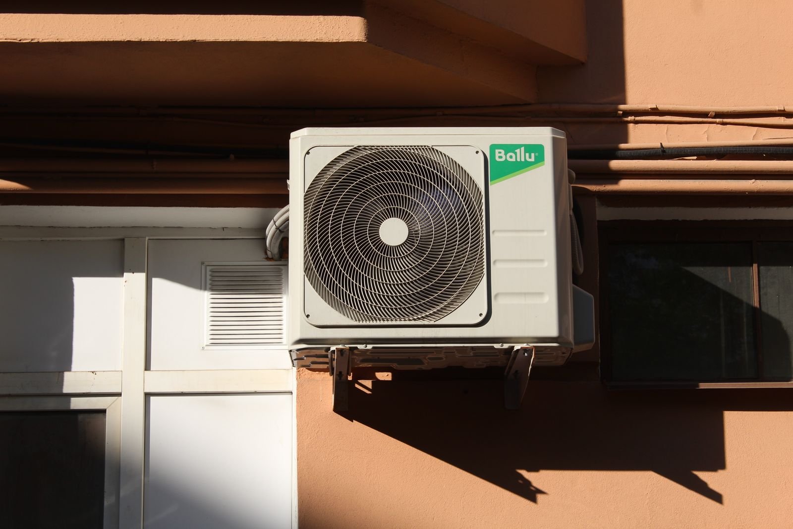 Outdoor central air conditioning condenser unit running next to a house during a summer power outage