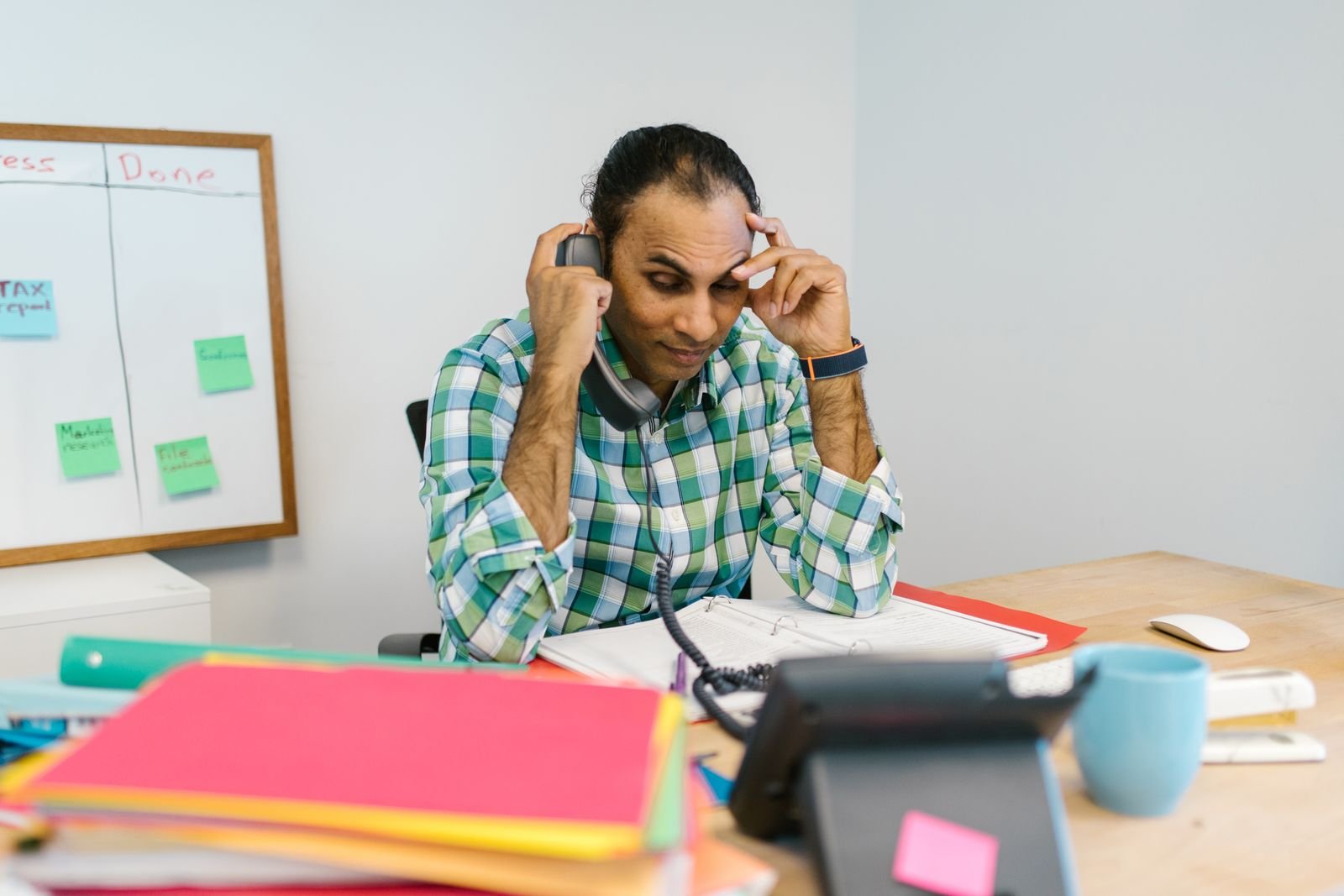 A homeowner on the phone surrounded by solar contracts and utility bills